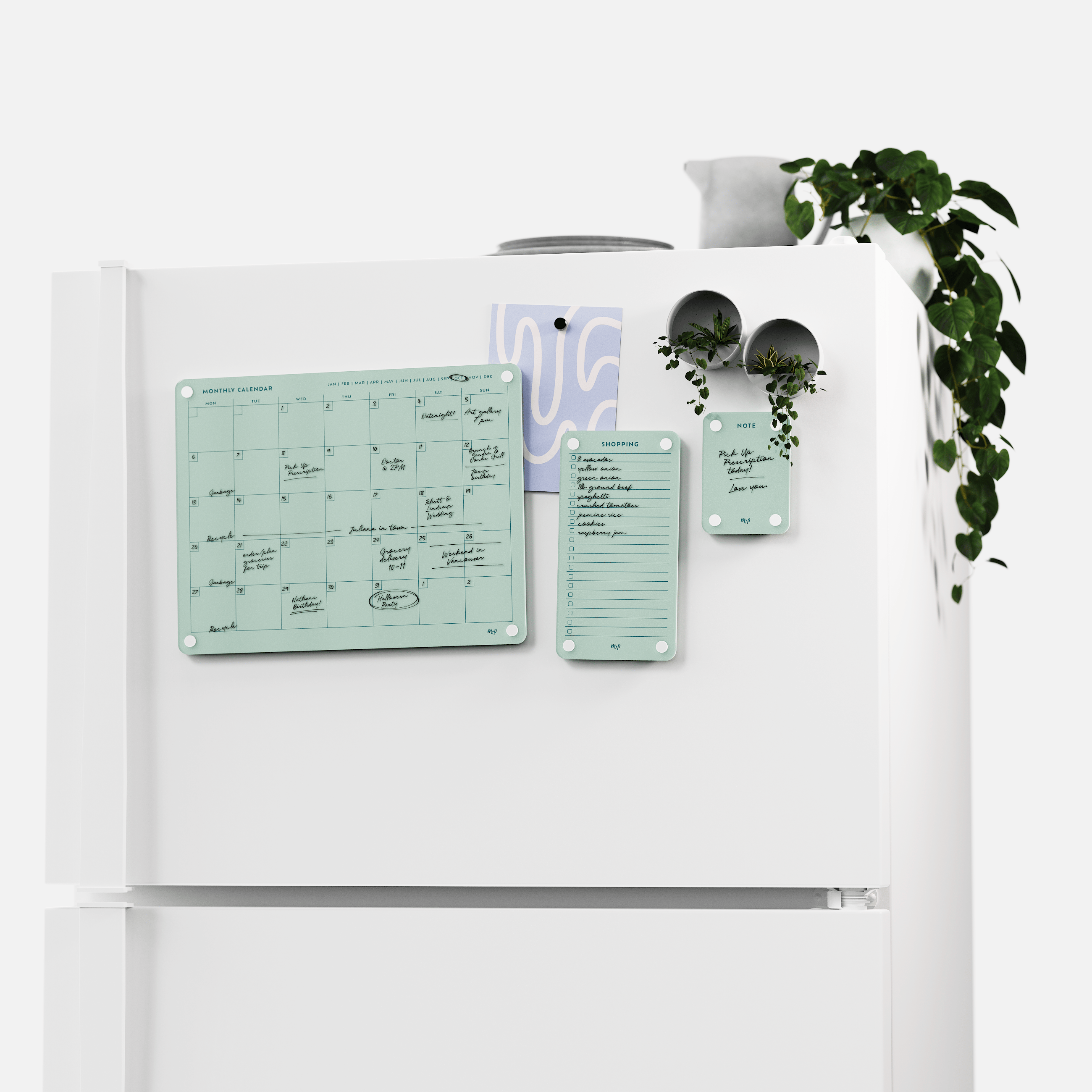 White fridge with the Seafoam green monthly calendar, shopping list and note board set, plants on top